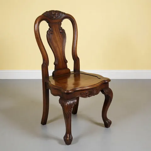 Restored antique wooden chair with glossy finish and carved details on gray floor against pale yellow wall