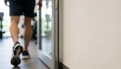Blurred gym background featuring a textured wall and door frame, suitable for promotional training text overlays.