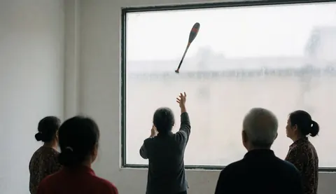 A person throws a club in a gym with white walls while other adults watch from behind in a calm and realistic scene