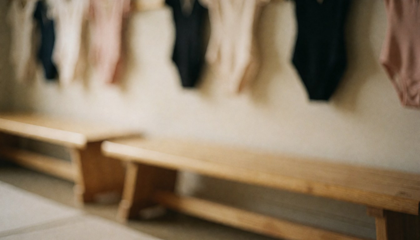Soft-toned gymnastics locker room background featuring wooden benches and hanging leotards, ideal for text overlays and design projects.