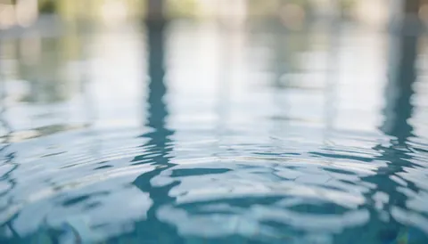 Serene blue water surface with soft reflections, serving as a calm and professional background for swimming business text overlays.