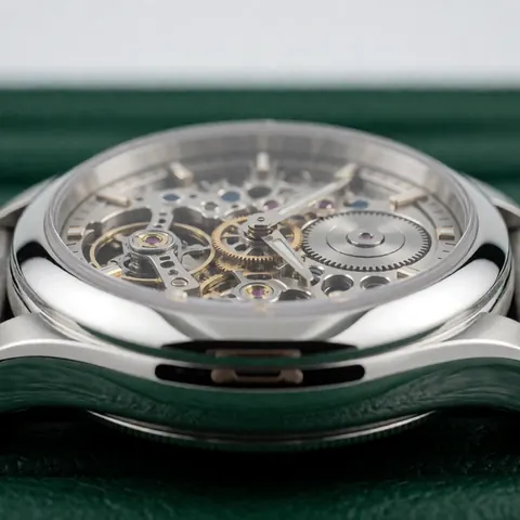 Close-up of a mechanical skeleton wristwatch showing gears and balance wheel on dark green velvet