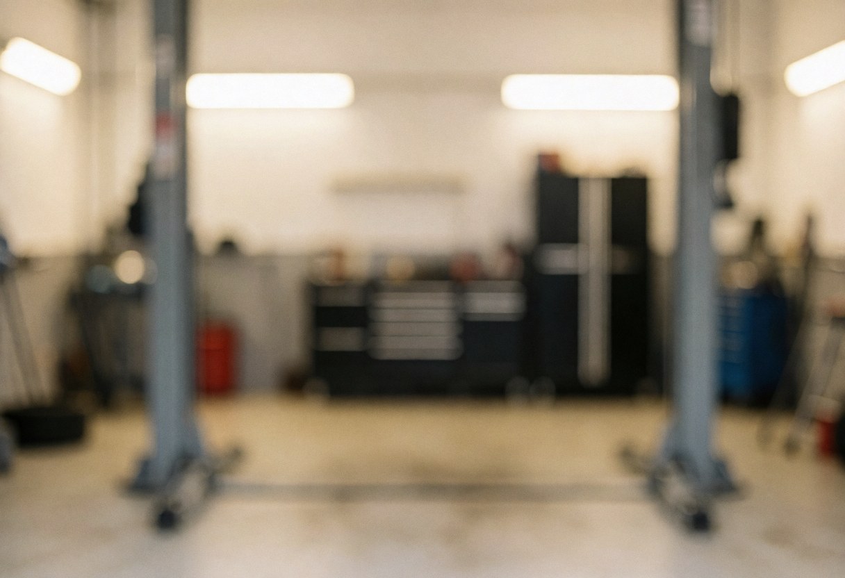 Out of focus background of an automotive paint shop featuring a tool cart, lift structure, and warm lighting suitable for websites