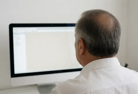 Professional auto body painter reviewing a paint formula on a computer screen in a clean white office.