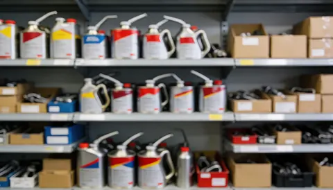 Blurred background of metal shelves stocked with oil bottles and spare parts boxes for a motorcycle repair shop, suitable for text overlay