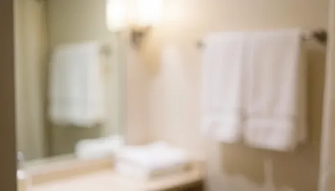 White towels hanging in a bathroom with a mirror and warm lighting, suitable for spa and massage service backgrounds