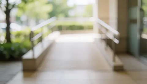 Accessible ramp with metal railings and soft natural light against a blurred vegetation background, suitable for commercial text overlays