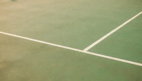 Green sports court surface with white boundary lines, serving as a clean background for text overlays.