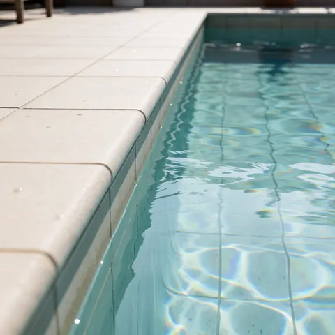 A public swimming pool featuring crystal clear water and a clean tiled deck, ideal for relaxation and sunbathing in a modern outdoor setting.