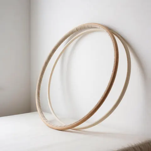 Two natural wooden gymnastic rings placed on a white surface with soft lighting and white walls, suitable for sports equipment product displays.