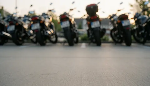 Motorcycles parked in a lot at sunset with clean pavement and a blurred background, ideal for a motorcycle repair shop text overlay.