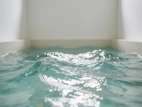 Close-up of turquoise saltwater ripples and sunlight shimmering on the surface of a public swimming pool with white walls