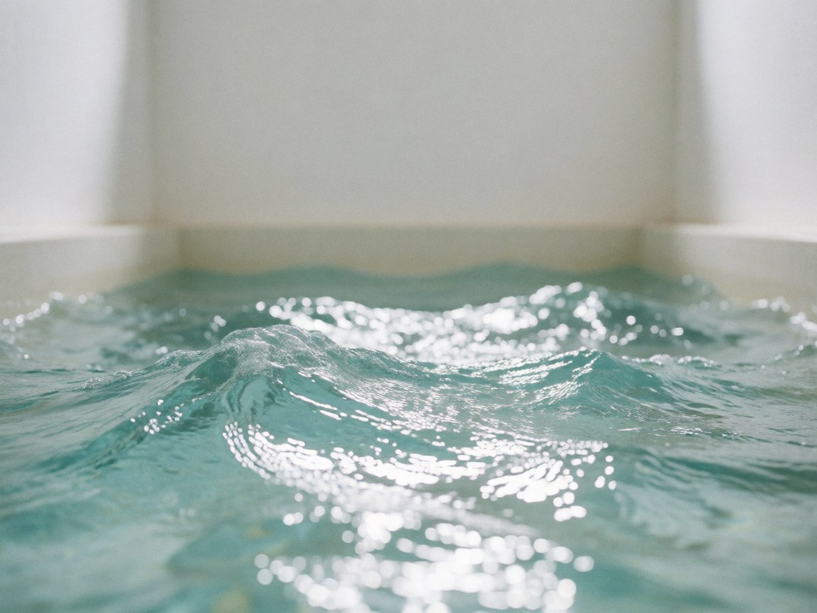 Close-up of turquoise saltwater ripples and sunlight shimmering on the surface of a public swimming pool with white walls