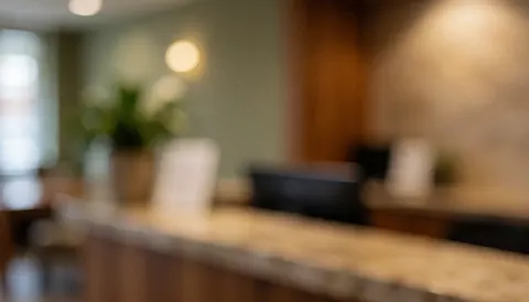 Wooden reception desk in a wellness center with a potted plant, wall lamp, warm lighting, and a relaxed atmosphere