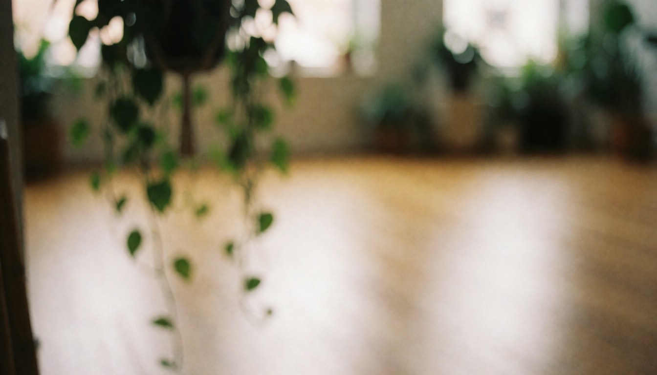 Soft light illuminates hanging plants and wooden flooring in a calm yoga studio interior, creating a relaxing background for text.