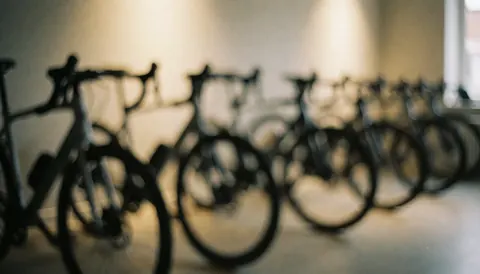 Row of racing bicycles with a blurred background and warm lighting, suitable for text overlay on a website header.