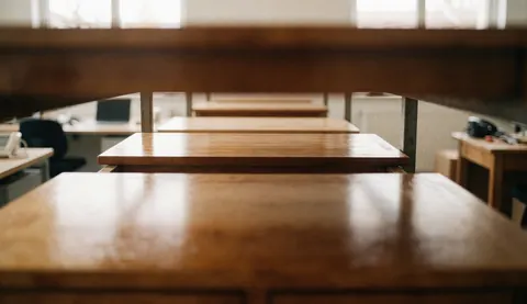 Close-up view of polished wooden tables in a woodworking shop with natural light, suitable as a background for text overlays.