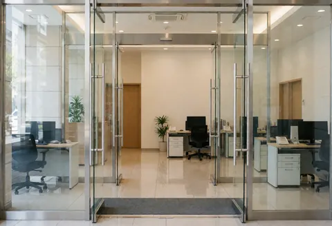 Modern office entrance featuring glass doors, polished floors, and clean furniture, ideal for professional cleaning services.