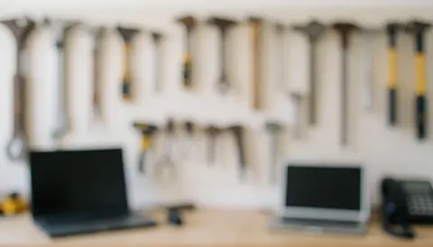 Workshop background with tools hanging on a white wall, work tables, and laptops, ideal for motorcycle repair services.