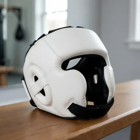 White boxing helmet with black straps resting on a wooden bench in a gym with gray walls and a mirror