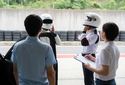 Marshal with clipboard reviewing driver in pit lane with tire and concrete barriers
