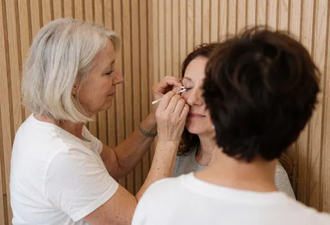 Close-up of a professional lash technician applying eyelash extension product to a client in a studio with wood walls