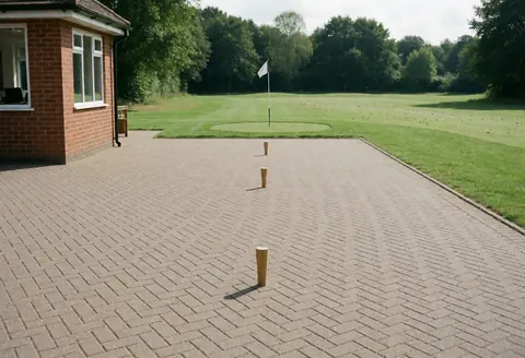 Three golf tees placed on a tiled pavement next to a golf club, suitable for golf instructor storefront or interior use