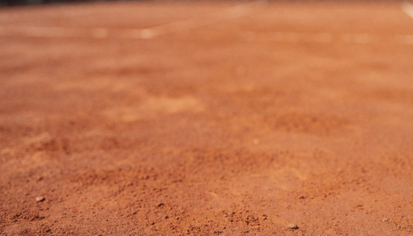 Out of focus red clay tennis court surface with natural lighting, serving as a textured backdrop for sports service text