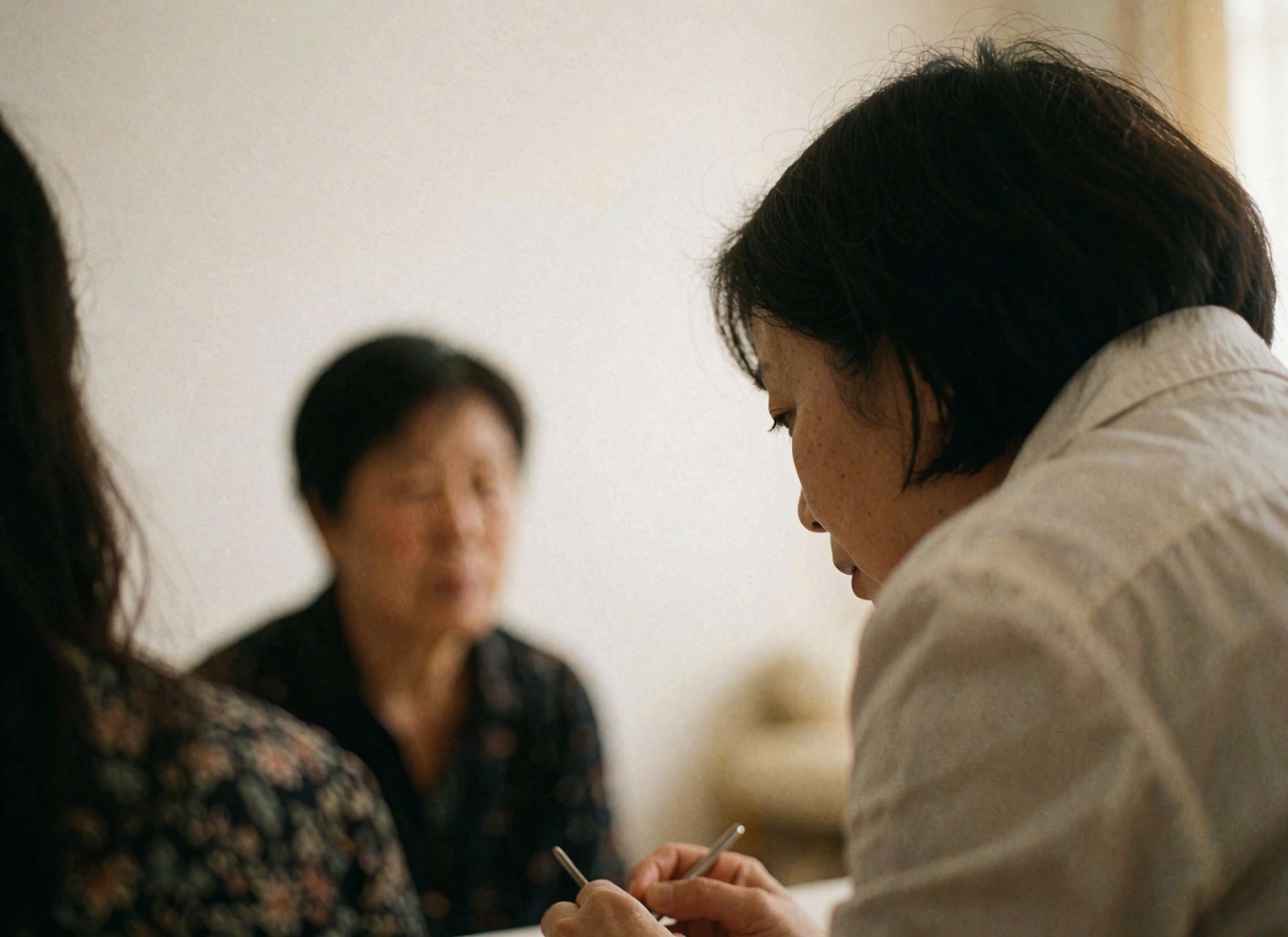 A homeopath practitioner writing notes on paper during a patient consultation in a professional setting with warm lighting.