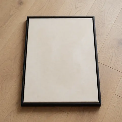 Thin black frame containing abstract artwork placed on a light wooden floor, ready for shipping to an online store.