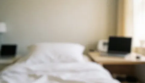Soft focus background of a hotel room featuring a bed and nightstands with neutral walls and gentle lighting suitable for text overlay