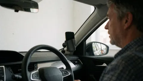 Close-up view of a smartphone secured by a magnetic mount attached to a car's air conditioning vent with steering wheel visible in background