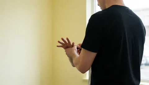 A boxing trainer wraps a client's hands in a gym with cream walls and natural light.