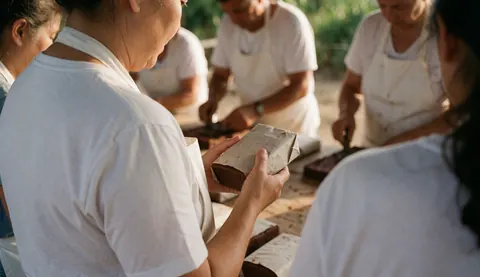 Worker packing block cacao in outdoor drying yard under natural light