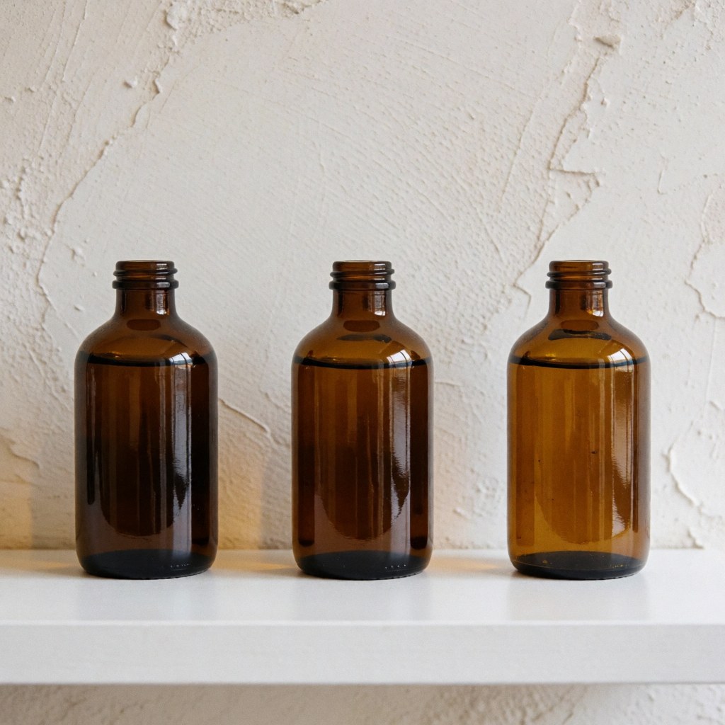 Three brown glass bottles of cervical massage oil arranged on a white shelf against a textured wall with natural lighting for a wellness clinic