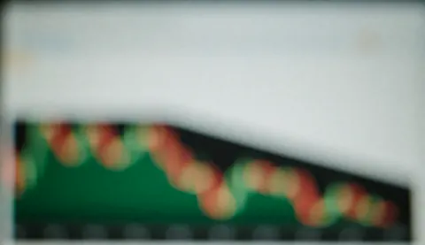 Blurred financial charts with bokeh effect on screen, serving as a background for finance and banking text.