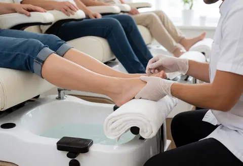 Close-up of a manicurist wearing gloves performing a pedicure service in a clean and professional salon setting