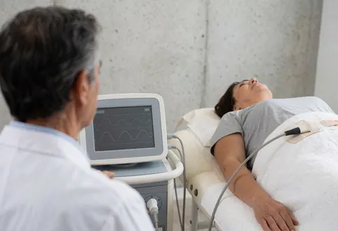 A therapist monitors the display of an electrotherapy device while a patient receives treatment in a clinical setting.