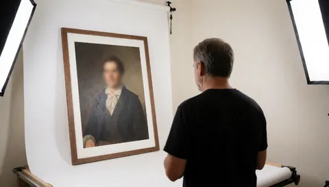 Portrait photographer reviewing a framed portrait in a studio with white background and softbox lighting