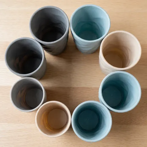 Reusable silicone cups arranged in a circle on light wood with neutral tones and flexible texture, ideal for business menus or catalogs