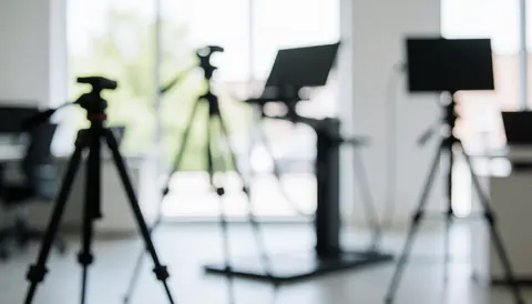 Studio background featuring tripods, a bike fitting station, and lighting equipment on a shiny floor with white walls, suitable for text overlay.