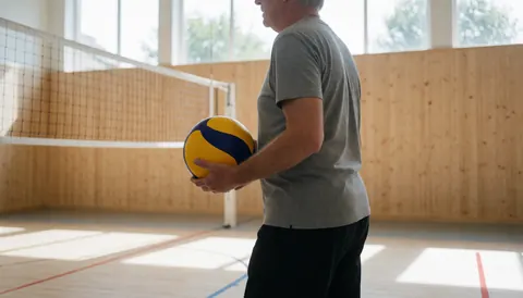 Volleyball coach holding a ball on an indoor court with wooden walls and natural light, ideal for a website hero section