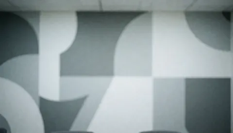 Abstract geometric mural in gray and white on an office wall, serving as a clean background for corporate text.