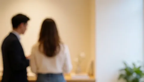 Two individuals seen from behind in a bright room with light walls and ample empty space on the right side, suitable for text overlay.