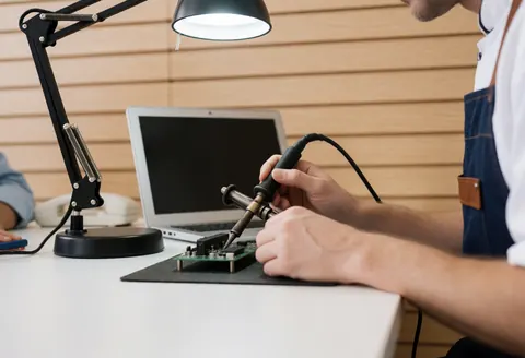 Close-up view of a technician soldering an electronic circuit board in a robotics workshop setting