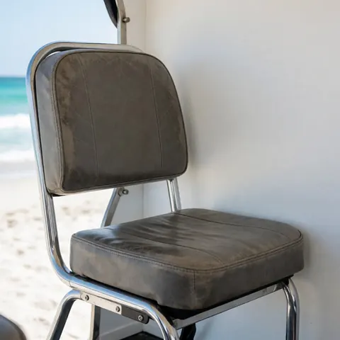 Worn gray leather bicycle taxi seat with chrome frame against a beach background with turquoise ocean