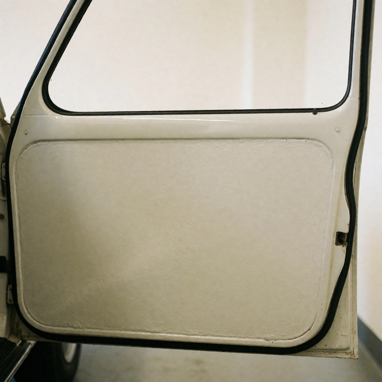 Close-up of a car door featuring smooth, uniform paint with sharp reflections against a warm white wall, ideal for auto body painting services.
