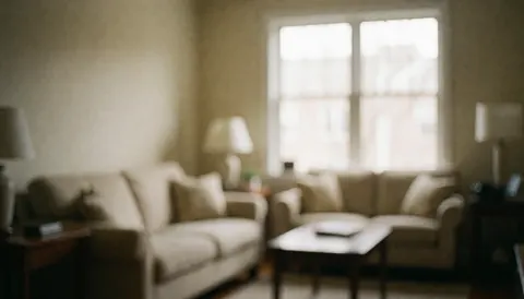 Soft focus interior of a cozy living area featuring a sofa, coffee table, and natural light from windows, suitable as a background for apartment hotel marketing.