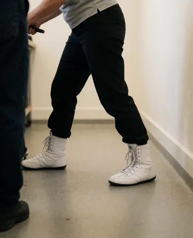 White boxing shoes positioned in a training stance on a rubber floor within a gym setting.