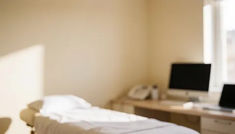 A massage table covered with white sheets in a room with beige walls and natural light